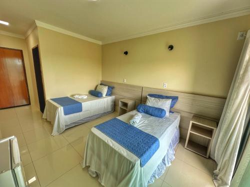 a hotel room with two beds with blue pillows at Hotel Aconchego do Velho Chico in Piranhas