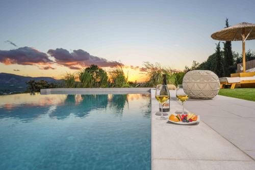 una piscina con 2 copas de vino y un plato de fruta en Villa Capparis, en Moírai