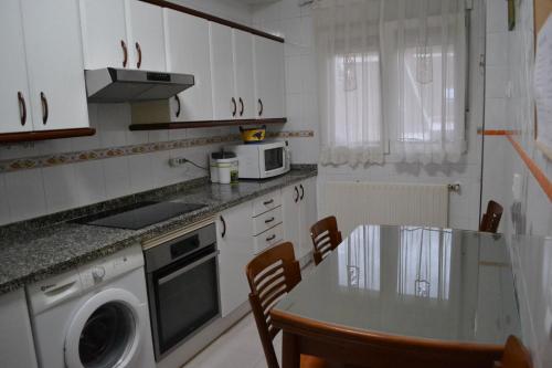 una cocina con armarios blancos y una mesa con sillas. en Vivienda Falda del Monsacro en Santa Eulalia de Morcín