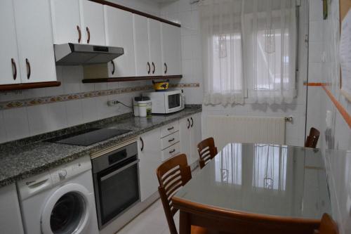 eine Küche mit weißen Schränken und einem Tisch mit Stühlen in der Unterkunft Vivienda Falda del Monsacro in Santa Eulalia de Morcín