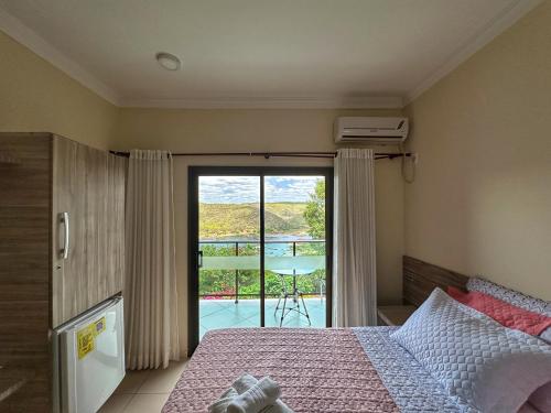 a bedroom with a bed and a view of a balcony at Hotel Aconchego do Velho Chico in Piranhas