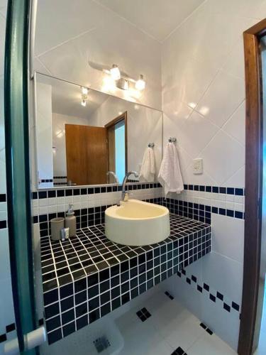 ein Bad mit einem Waschbecken und einem Spiegel in der Unterkunft Excelente casa na Praia do Cassino, RS in Rio Grande