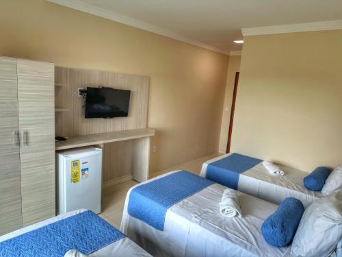 a hotel room with two beds and a flat screen tv at Hotel Aconchego do Velho Chico in Piranhas