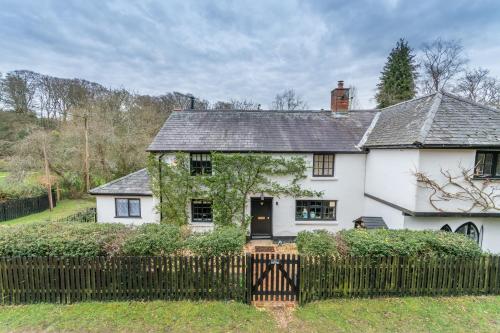 a white house with a fence in front of it at Luxury cosy cottage, enchanting forest location. in Ringwood