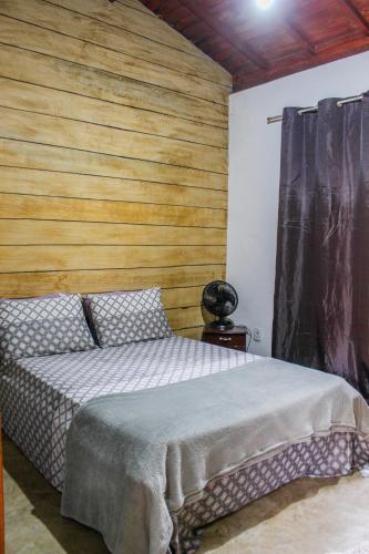 a bedroom with a bed and a wooden wall at Casa Da Cléo Carrancas in Carrancas