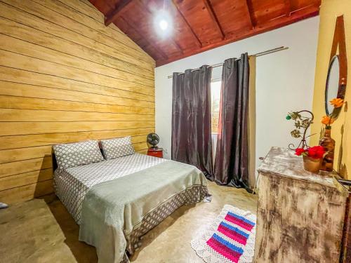 a bedroom with a bed and a wooden wall at Casa Da Cléo Carrancas in Carrancas