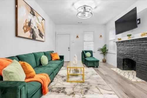 a living room with a green couch and a fireplace at Near River St, Forsyth & DT - Stylish - Free Parking in Savannah