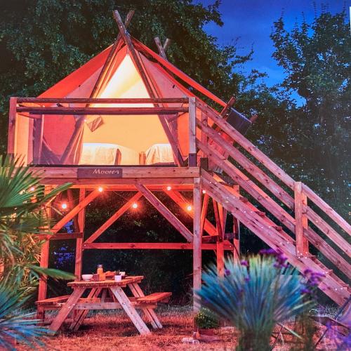 a tree house with a table in front of it at TENTE AU PLUS PROCHE DES ÂNES in Bressuire
