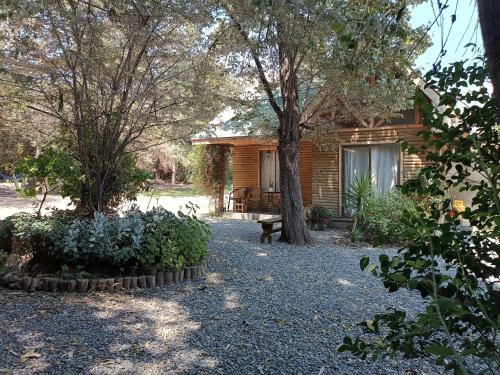 a house with a bench in front of a yard at Cabaña El Tiempo Es Arte in San José de Maipo