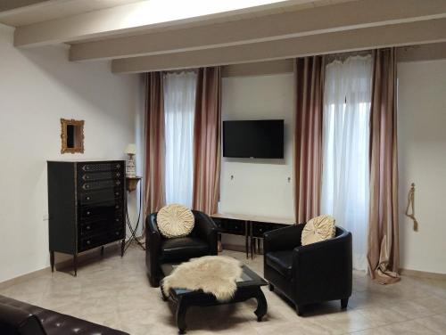 a living room with two chairs and a flat screen tv at Affittacamere Vicino al Porto in Porto Torres