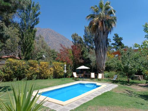 una piscina en un patio con una palmera en Cabaña El Tiempo Es Arte, en San José de Maipo