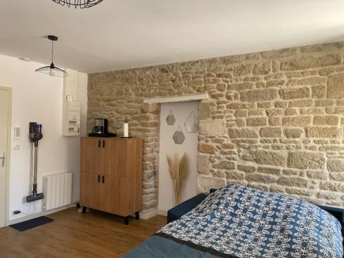 - une chambre avec un mur en pierre, un lit et une commode dans l'établissement Guérande, studio entier intra-muros, à Guérande