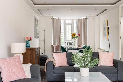 - un salon avec deux canapés gris et des oreillers roses dans l'établissement 6-bedroom LUX House next to Hyde Park &Marble Arch, à Londres