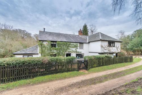 a white house with a fence in front of it at Luxury cosy cottage, enchanting forest location. in Ringwood