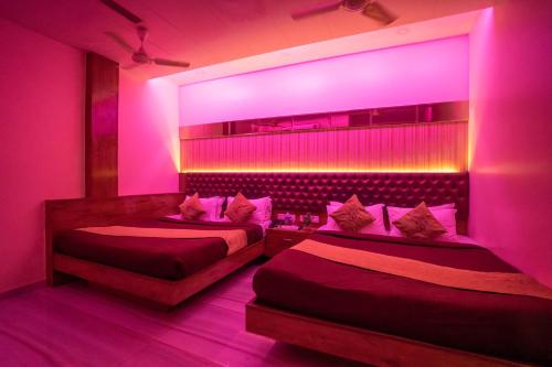 two beds in a room with pink lighting at Hotel Royce Executive Near US Consulate, Bandra Kurla Complex in Mumbai