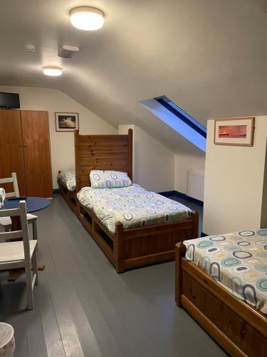 1 dormitorio con 2 camas, mesa y sillas en Coastguard Lodge Hostel at Tigh TP, en Dingle