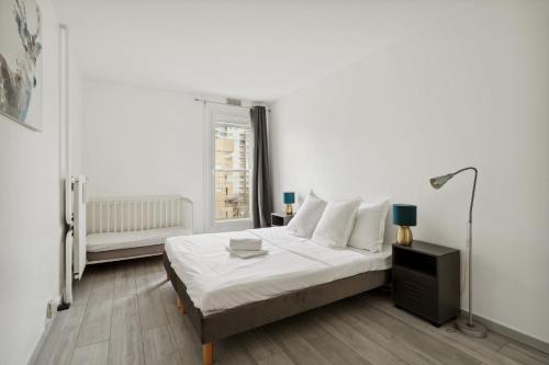 a white bedroom with a bed and a lamp at Large family T3 with parking near La Défense in Nanterre