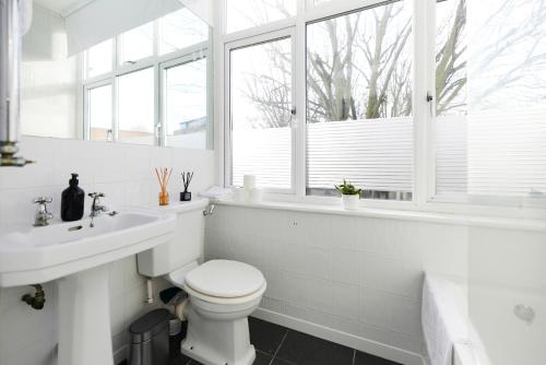biała łazienka z toaletą i umywalką w obiekcie The Putney Hideout - Bright 1BDR Flat w Londynie