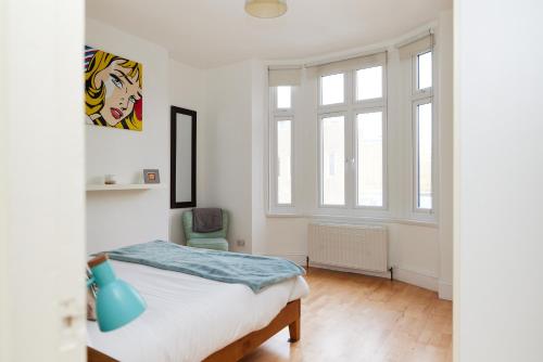 biała sypialnia z łóżkiem i oknem w obiekcie The Putney Hideout - Bright 1BDR Flat w Londynie