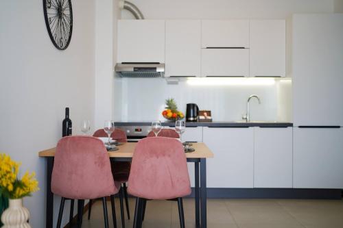 a kitchen with a wooden table with pink chairs at Royal apartment Salona in Klis