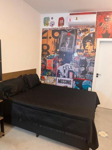 Bett in einem Zimmer mit einer mit Aufklebern bedeckten Wand in der Unterkunft Pousada Bat N Breakfast No Beco do Batman in São Paulo