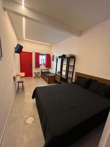 a bedroom with a black bed and a living room at Pousada Bat N Breakfast No Beco do Batman in Sao Paulo