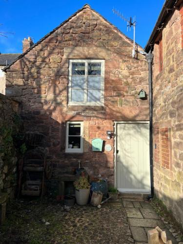 ein Steinhaus mit einer weißen Tür und einem Fenster in der Unterkunft Rowan Cottage in Cromford