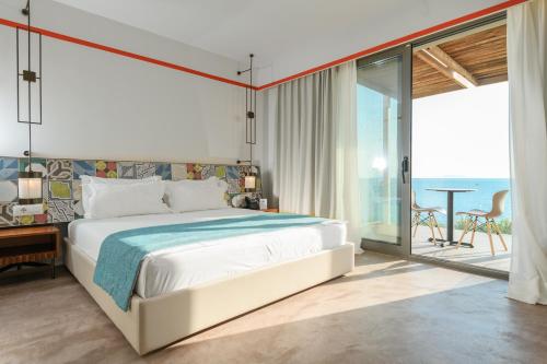 a bedroom with a bed and a view of the ocean at Folie Marine Hotel & Beach Club in Jal