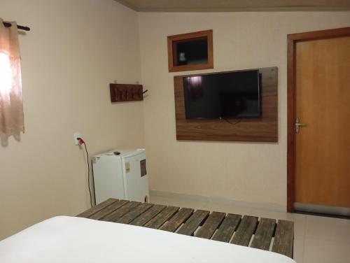 um quarto com uma cama e uma televisão na parede em Suítes Pirenópolis Piri em Pirenópolis