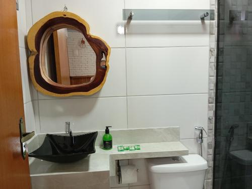 een badkamer met een wastafel en een spiegel boven een toilet bij Suítes Pirenópolis Piri in Pirenópolis