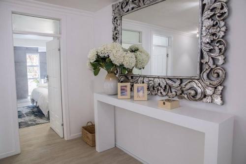 um espelho numa parede num quarto branco com flores em Modern Luxury Beach House em Ballito