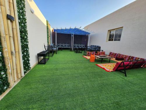 a patio with green grass and couches on a building at استراحة وشاليه وقاعة السلطانه رجال in Al-Salam