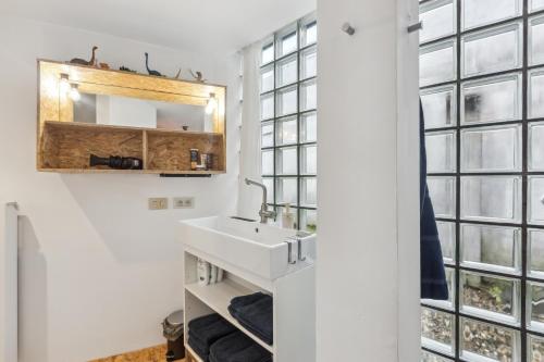 a bathroom with a sink and large windows at Cosy art studio near station with bikes and garden in Ghent