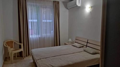 um pequeno quarto com uma cama e uma janela em Тристаен Апартамент- em Sveti Vlas