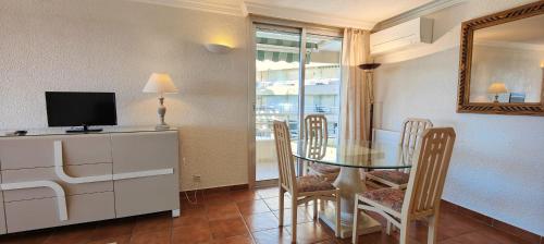 une salle à manger avec une table avec des chaises et une télévision dans l'établissement 50 m cocoon of Love with a common shared pool, à Saint-Raphaël