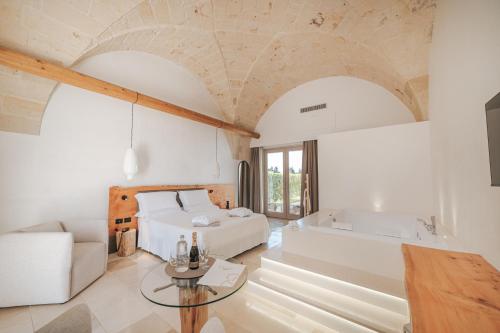 a bedroom with a bed and a tub and a table at Masseria Longa Boutique Hotel in Otranto