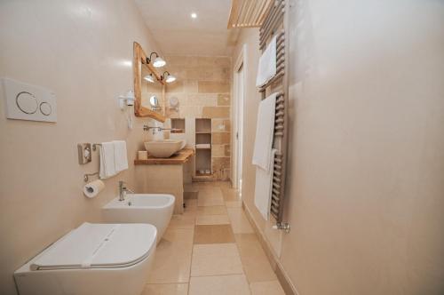 a white bathroom with a toilet and a sink at Masseria Longa Boutique Hotel in Otranto