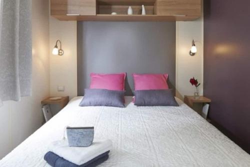 - une chambre dotée d'un grand lit avec des oreillers roses et bleus dans l'établissement Mobil-home 3 chambres 6-8 pers - Camping Lac des Rêves, Lattes, à Lattes