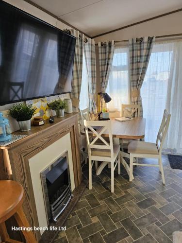 a living room with a fireplace and a table and a tv at Seascape Horizon at Camber Sands in Camber