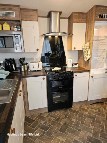 a kitchen with a black stove and a sink at Seascape Horizon at Camber Sands in Camber