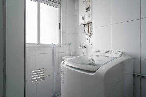 a white bathroom with a washing machine and a window at Acolhimento e Conexão: EXPO Center Norte in São Paulo