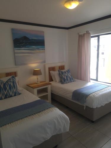 two beds in a room with a window at Plett Sunrise:) in Plettenberg Bay