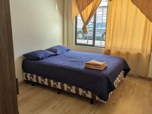 a bedroom with a bed with blue sheets and a window at Casa Crema in Cuenca
