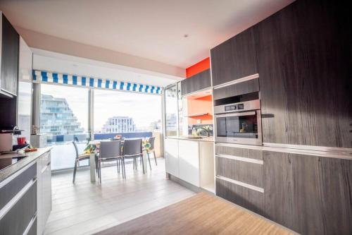 a kitchen with wooden cabinets and a table with chairs at Le Central Vue Mer Clim Plage 2min Cosy Confort - Jetservices Conciergerie in La Grande-Motte