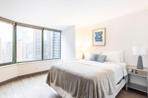 a white bedroom with a bed and large windows at ENVITAE 3BR Luxury Corner Loft with Navy Pier Views in Chicago