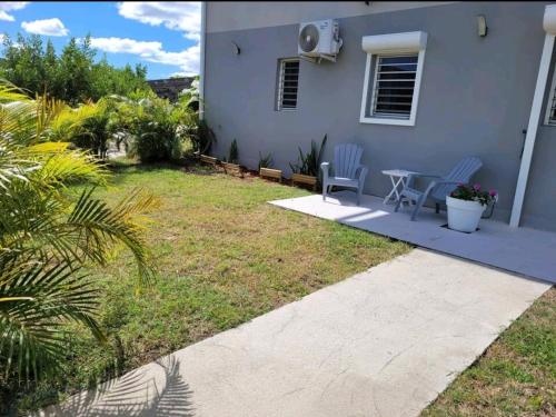 a house with two chairs and a table in the yard at Superbe appartement cosy neuf in Grand Case