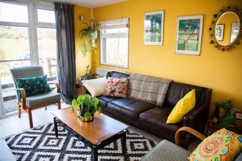 a living room with a couch and a table at The Deckhouse, cabin with big deck nr Hay-on-Wye in Rhos-gôch