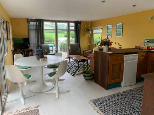 a kitchen with a white table and chairs in a room at The Deckhouse, cabin with big deck nr Hay-on-Wye in Rhos-gôch