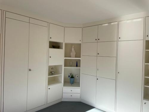 a white wardrobe in a room with white cabinets at Dünenrose 21 in Norderney
