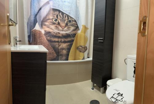 a cat in a shower curtain in a bathroom at Apartamento en Roquetas de Mar. in Aguadulce